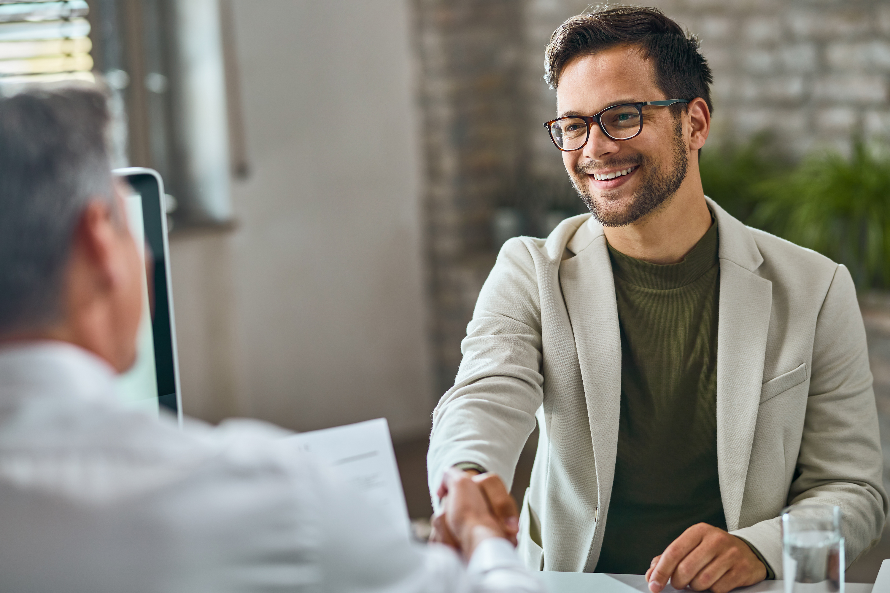 happy male candidate handshaking with manager after successful job interview office